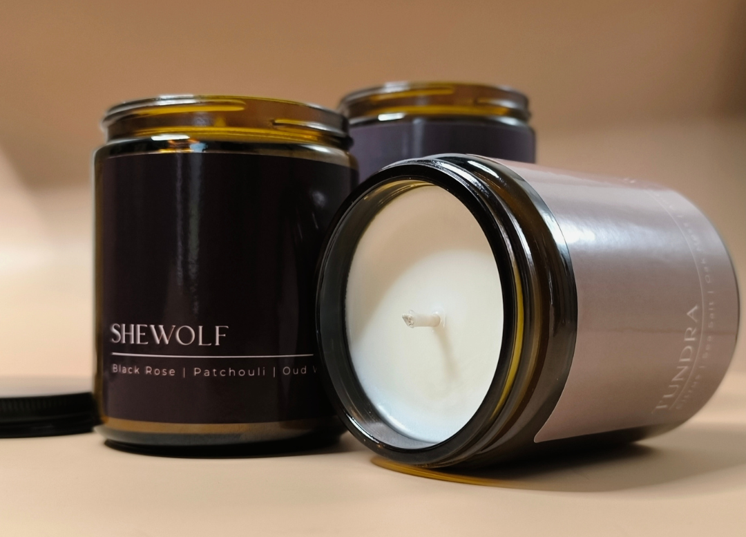 3 wolf candle co candles, Shewolf candle standing up, another candle laying down on its side displaying the wax and wick