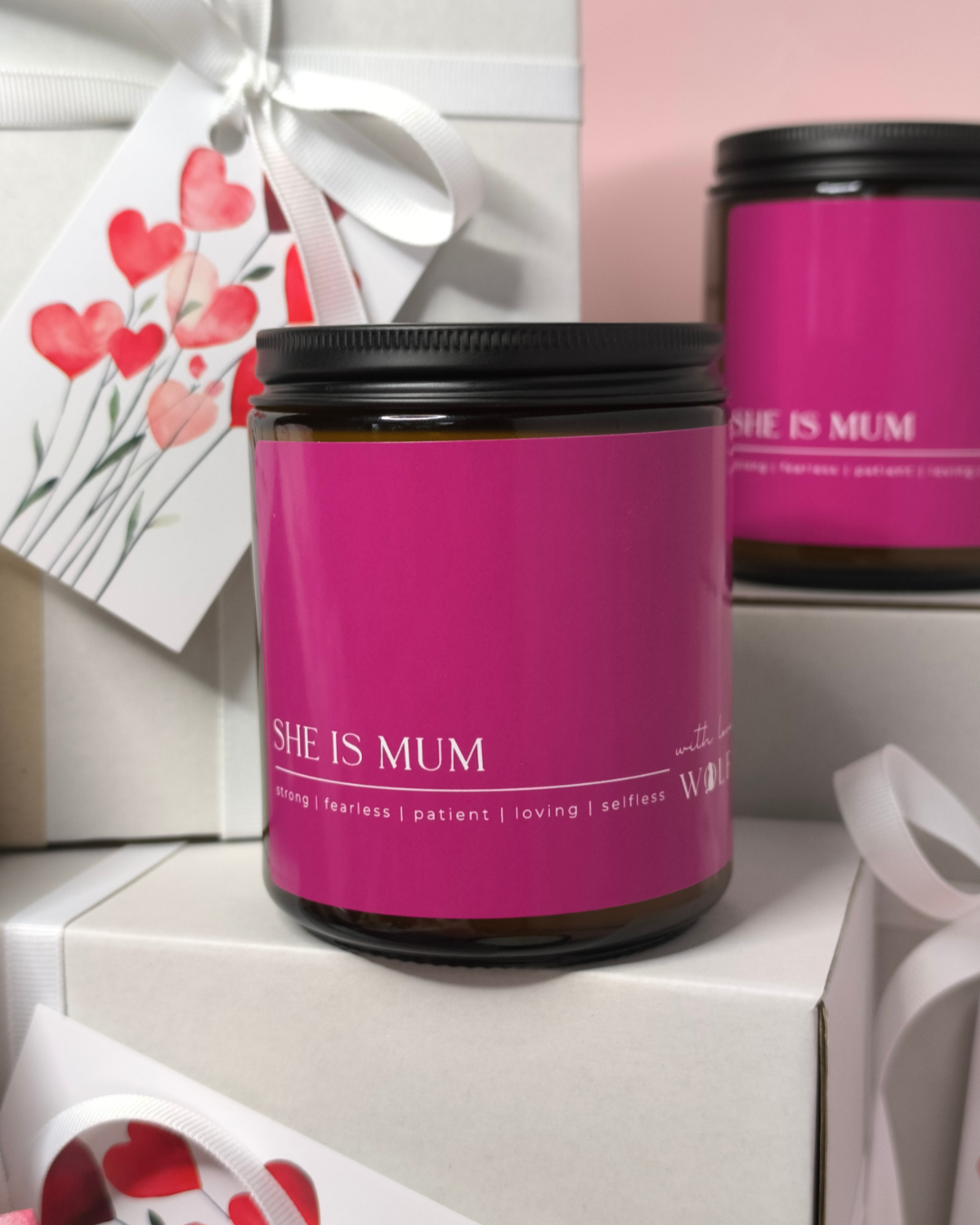Candle with 'SHE IS MUM' text on a pink background