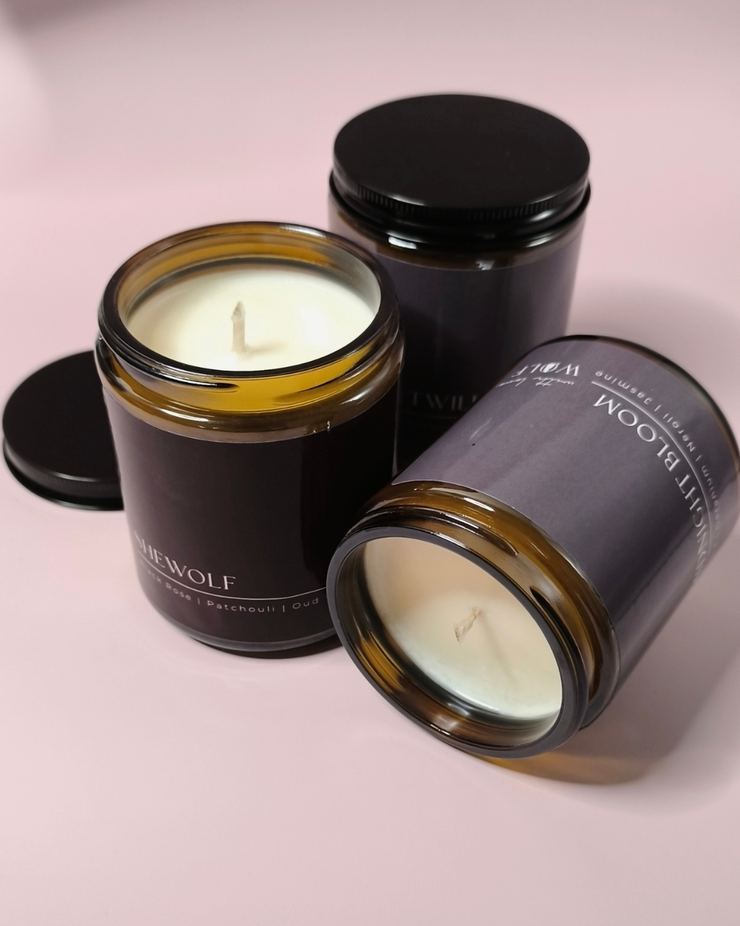 3 wolf candle co candles, Shewolf candle standing up, another candle laying down on its side displaying the wax and wick 
